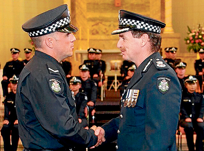 Well done: First Constable Cameron Wallace receives his Medal of Courage award from Acting Chief Commissioner Tim Cartwright at the police academy.