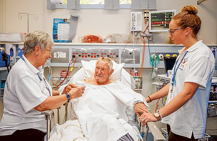 Work its own reward: Volunteers Dilys Yap and Meg Ridley assist a bed-ridden Laurence Jenny at Rosebud Hospital. Picture: Yanni