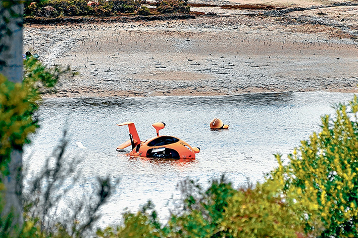 Death crash: A gyrocopter in which a pilot died lies in shallow water at Rutherford Inlet, near Cannon Creek. Picture: Donna Oates, Pakenham Gazette