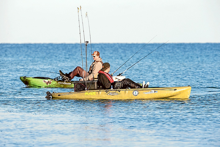 Helping out: The 47 kayakers who went fishing off Mt Martha and Sunday 8 November helped raise money for That’s The Thing About Fishing(TTTAF), a group that uses fishing as a therapy. Above, Luke Easton and Tim Heffernan go looking for fishing spots. Right, John Mauro, of Mt Eliza, with his catch, a flathead, and TTTAF founder Glenn Couper. Pictures: Gary Sissons