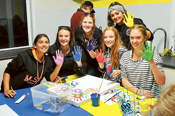 Hand signals: above, Jaia, Sophie, Morgan, Emily, Shontail, and Lily create a group art work during a youth leadership camp held by the Mornington Peninsula Partnership Forum. Below, Trinity on the giant swing.