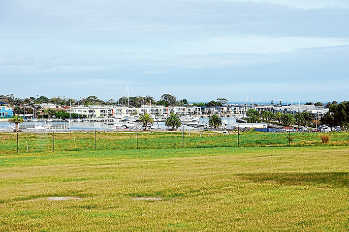 Close community: The green fields leading to the water’s edge at Martha Cove are earmarked for three-storey “townhomes” and shops, above; while, below, houses and apartments are already nearing completion overlooking the next staged development.