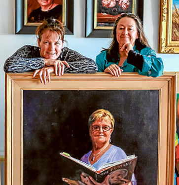 Doubling up: Fiona Bilbrough and Vicki Sullivan have combined their works for a portraits exhibition at Mornington Peninsula Regional Gallery. Theyt are pictured with Bilbrough’s “Attention Please” portrait of former primary school principal, Carol Norman. Picture: Supplied